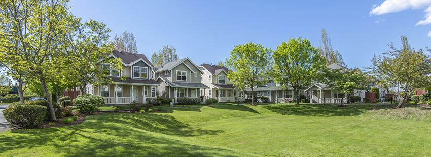 a row of houses on a green lawn with trees