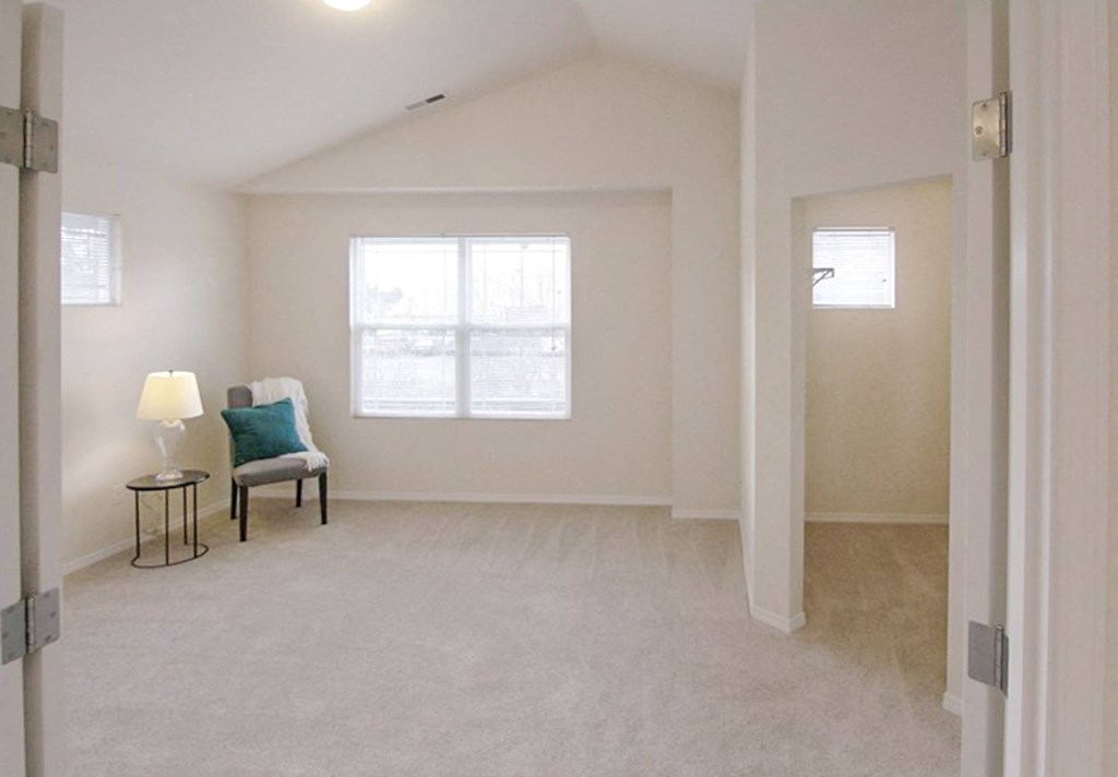 an empty living room with a chair and a window