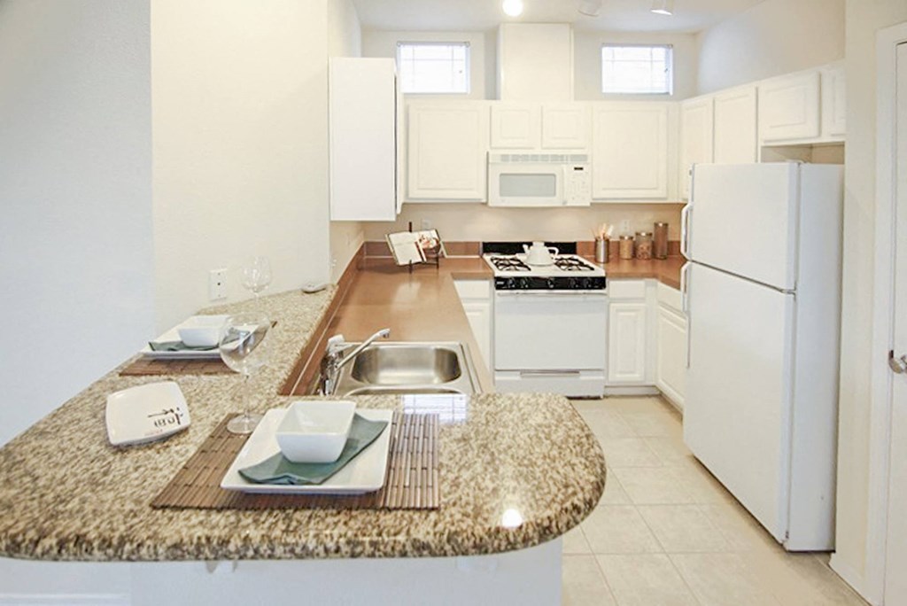 a large kitchen with white appliances and a granite counter top