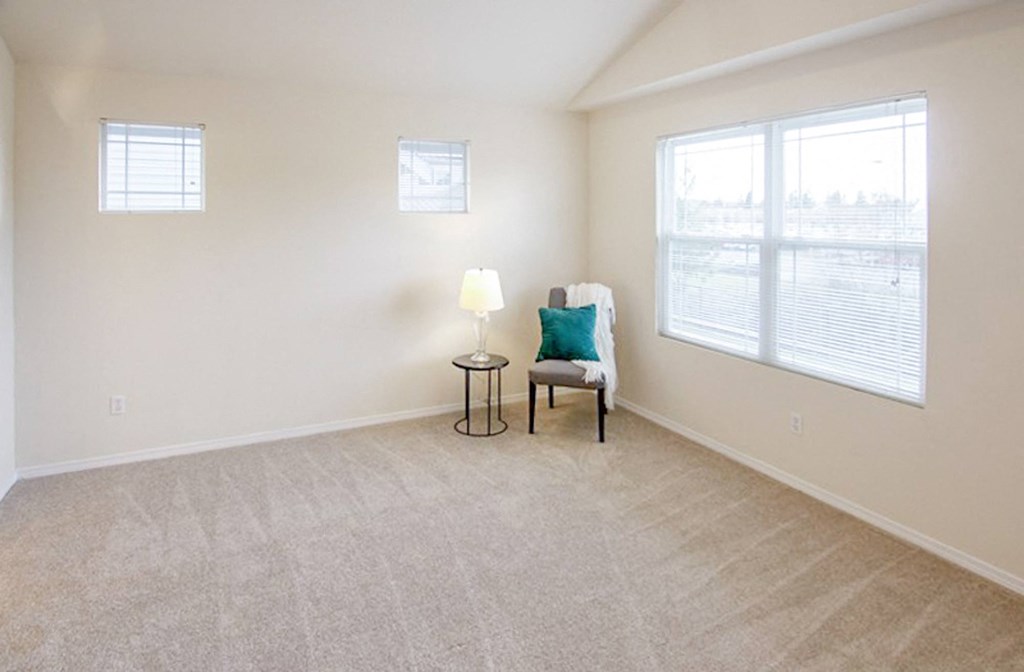 an empty living room with a chair and a window