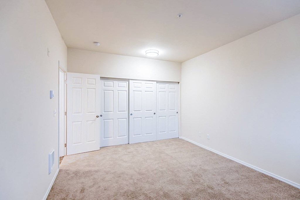 a bedroom with white walls and white doors and carpet