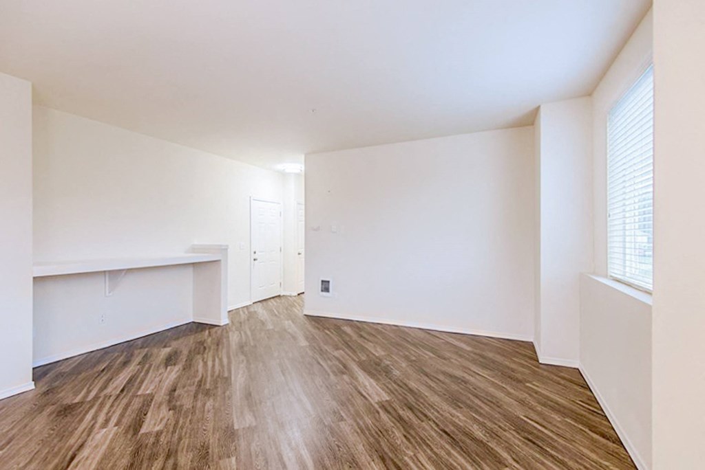 an empty living room with white walls and wood flooring