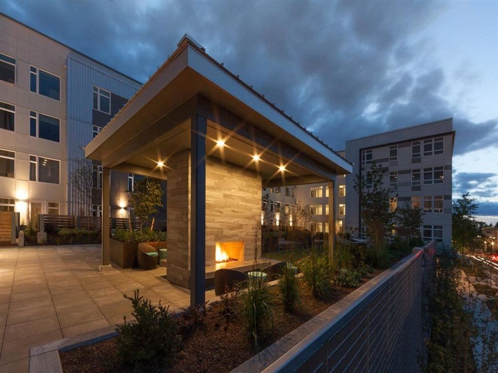 a covered patio with a fireplace at dusk