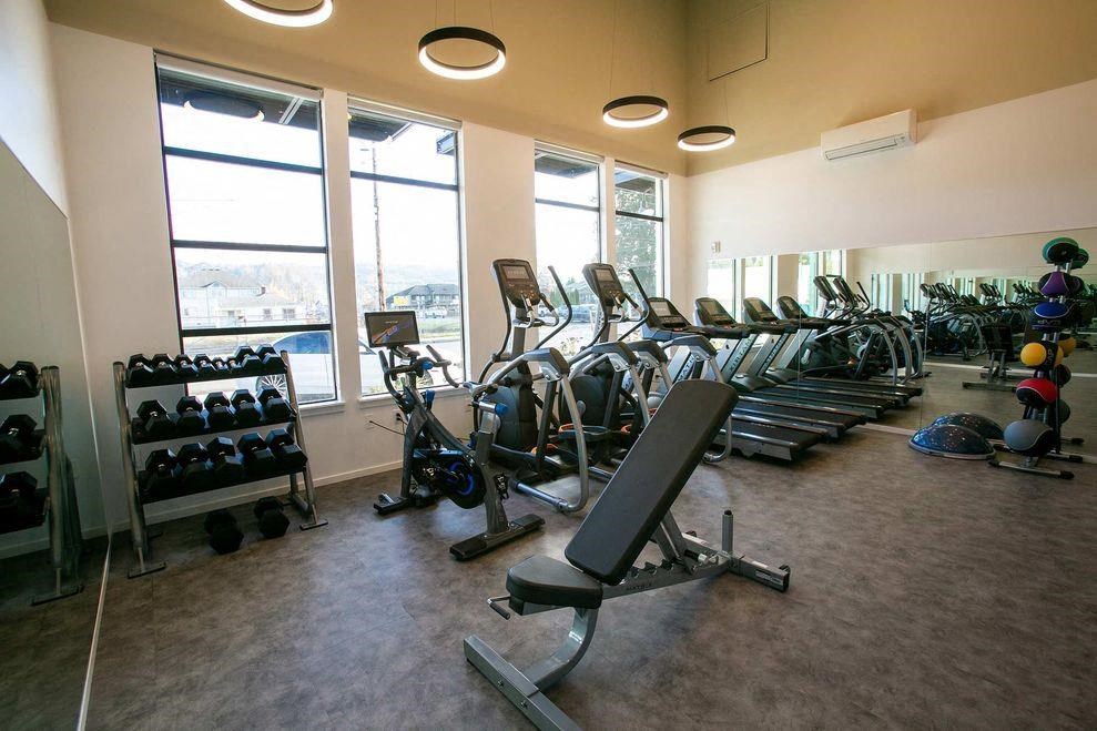 a gym with a row of exercise equipment and windows