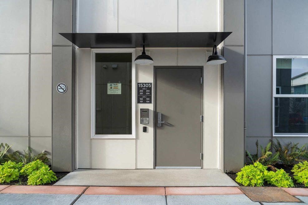 a door to a building with a sidewalk and plants