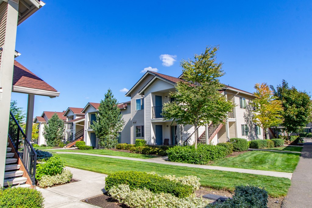a row of houses on a sidewalk with grass and trees