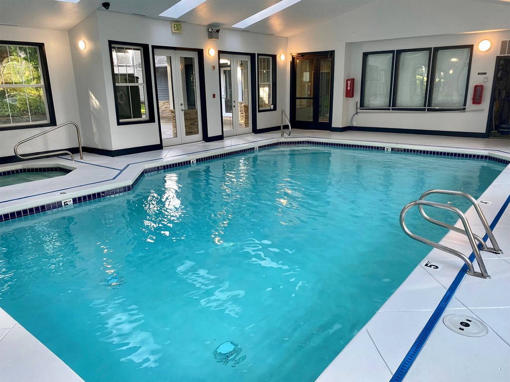 a swimming pool in a building with windows and a blue water