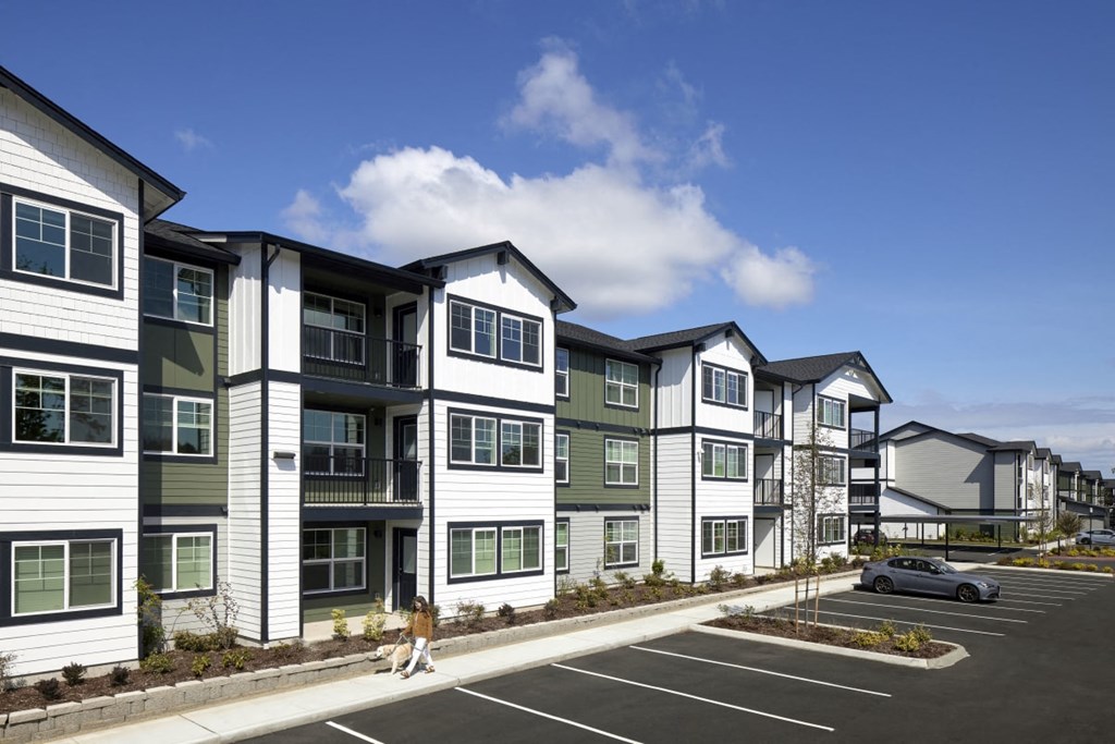 a rendering of a large apartment complex with a car parked in a parking lot