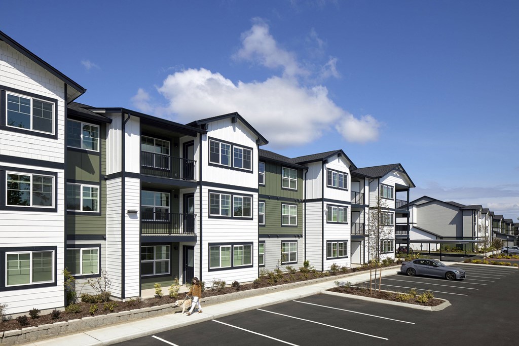 a rendering of a large apartment complex with a car parked in a parking lot