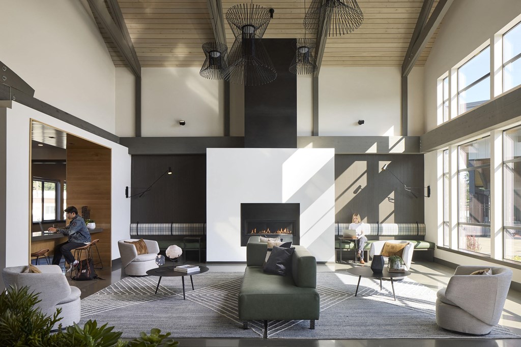 a view of the living room with a fireplace and a woman sitting at a desk in the