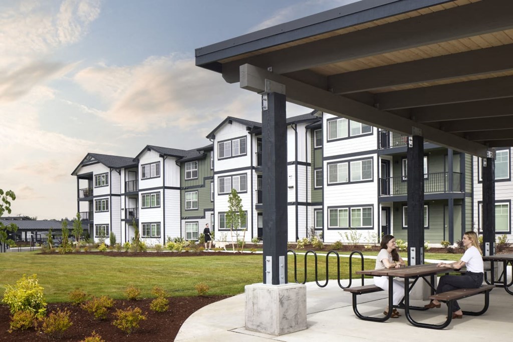 people sitting at a picnic table in front of an apartment building