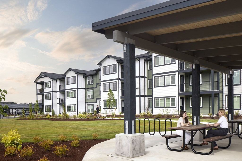 people sitting at a picnic table in front of an apartment building