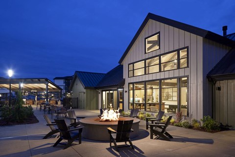 a patio with chairs and a fire pit outside of a building