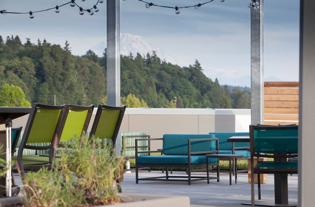 a patio with chairs and a table and a mountain in the background