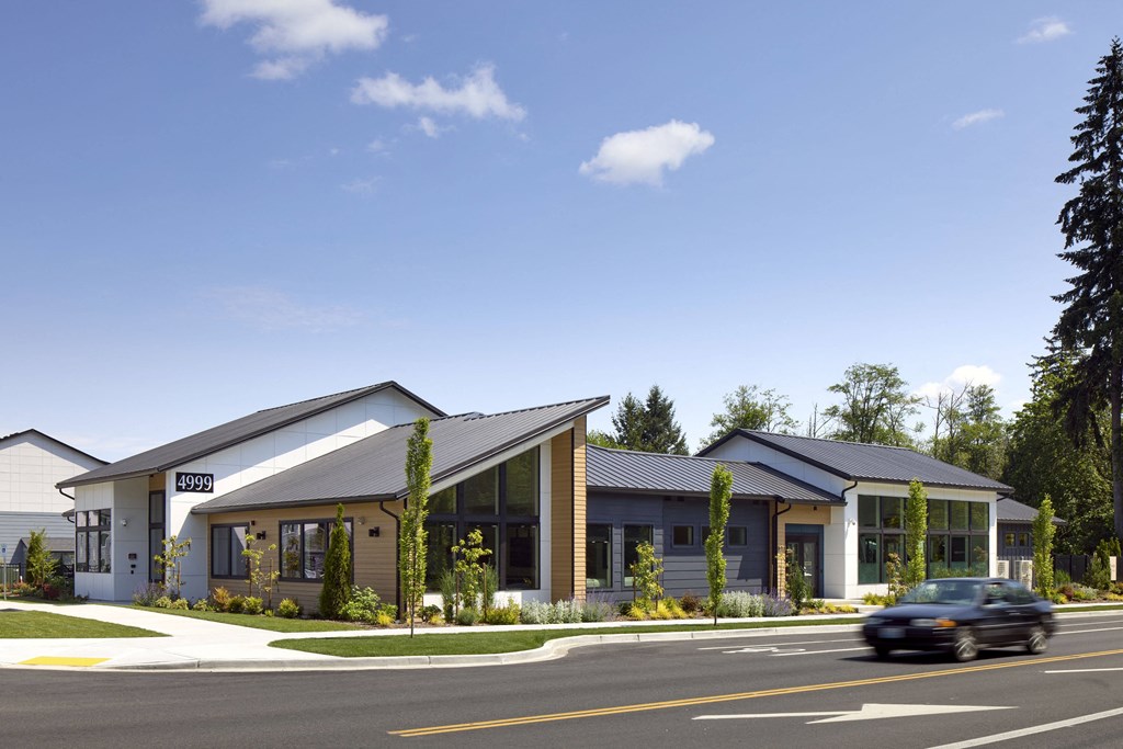 a rendering of the front of the building with a car driving by