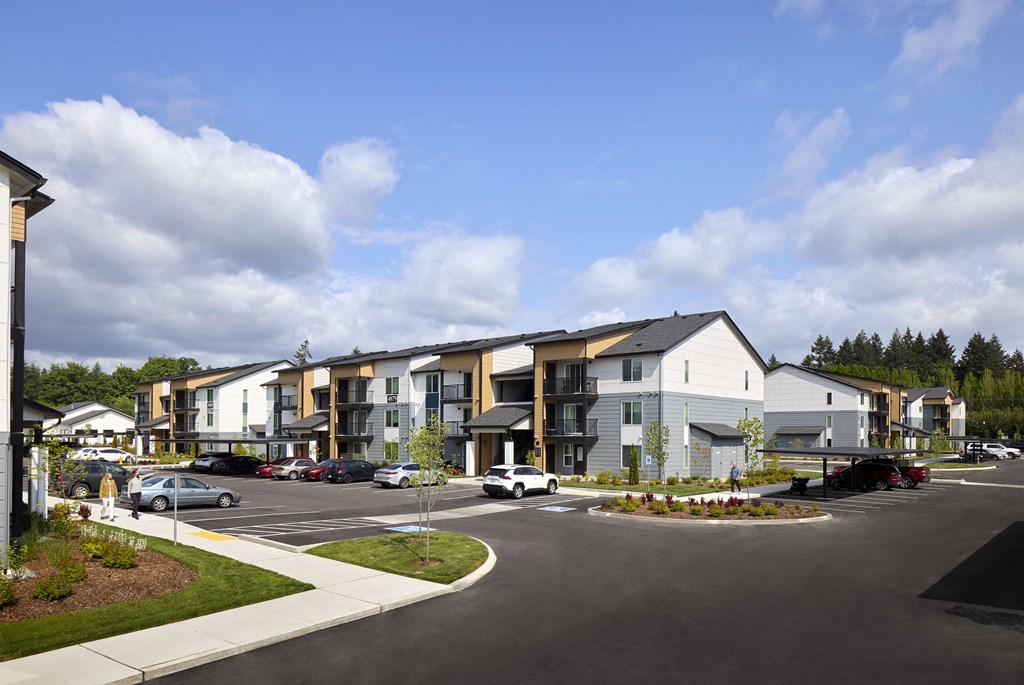 a rendering of an apartment complex with a parking lot in the foreground and buildings in the background
