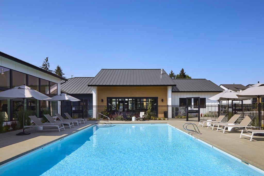 a swimming pool with lounge chairs and umbrellas in front of a building