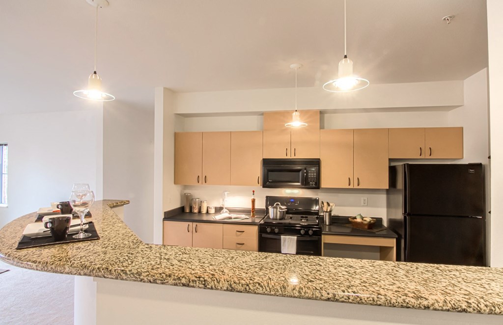 a kitchen with a granite counter top and a black refrigerator