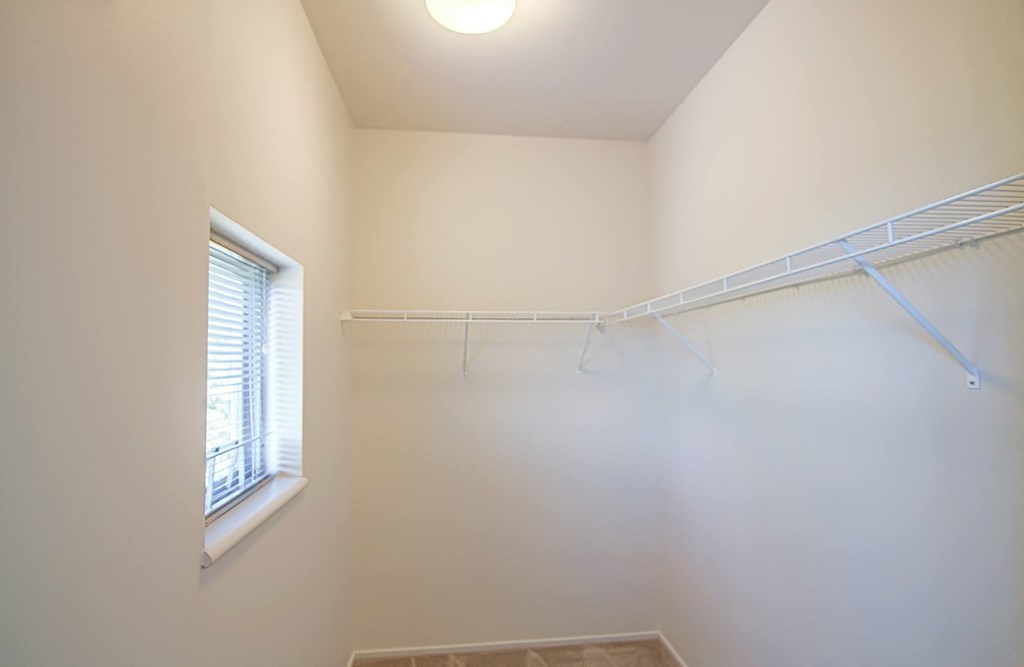 the closet in the master bedroom has a window and white walls