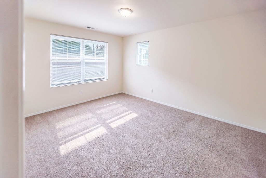 an empty living room with a window and carpet