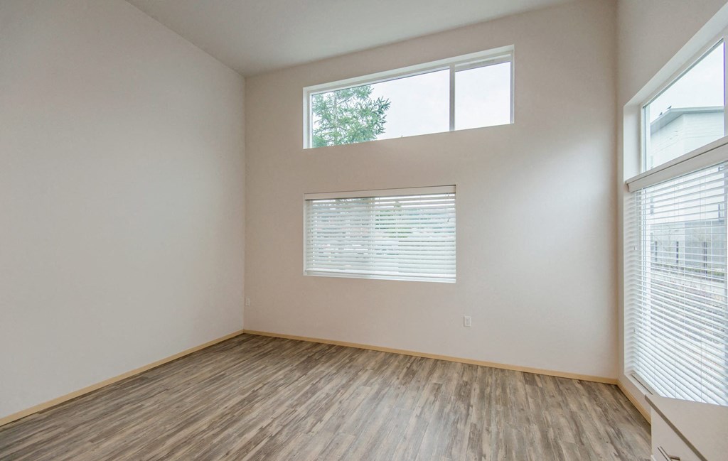 the spacious living room with large windows and wood flooring