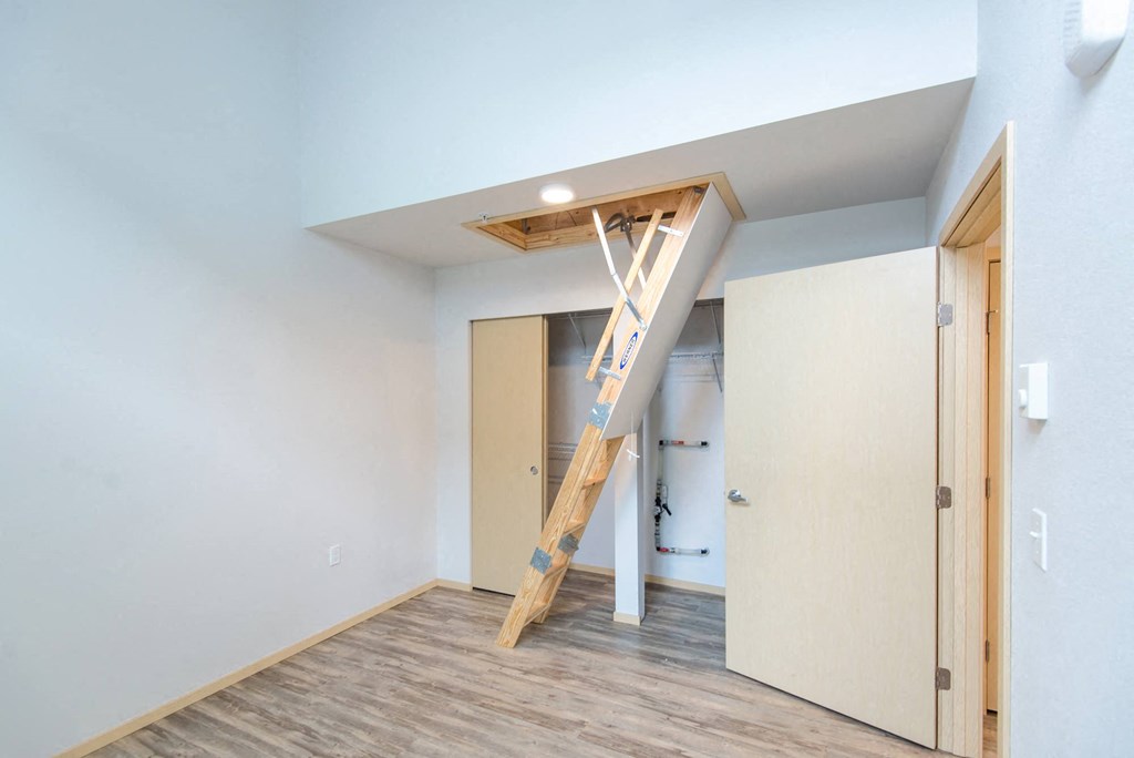a loft with a ladder in a room with a door