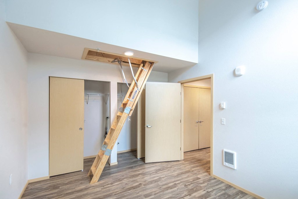 a loft with a ladder in a room with doors