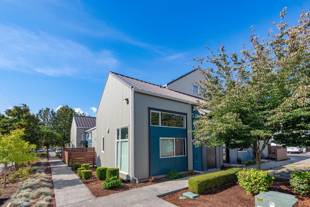 a gray and blue house with trees and a sidewalk