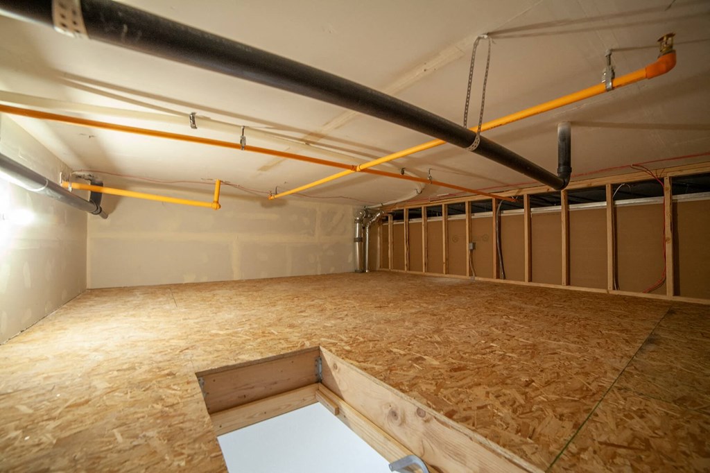 a large room with wood flooring and pipes in it