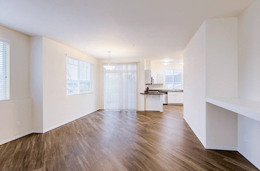 an empty living room with hard wood floors and a kitchen