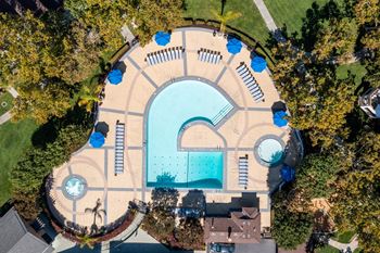 An aerial view of a swimming pool surrounded by trees at The Woods Apartments, California
