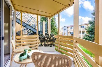 A patio with a chair and a table with a vase on it at The Woods Apartments, San Jose