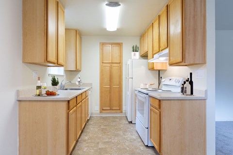 A kitchen with wooden cabinets and a white refrigerator at Cherrywood Apartments, San Jose, 95118
