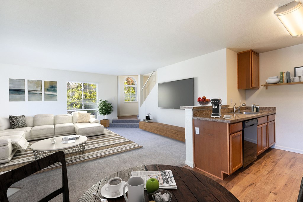 A modern living room with a white sofa and a wooden kitchen area at The Woods Apartments, California
