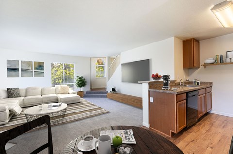 A modern living room with a white sofa and a wooden kitchen area at The Woods Apartments, California