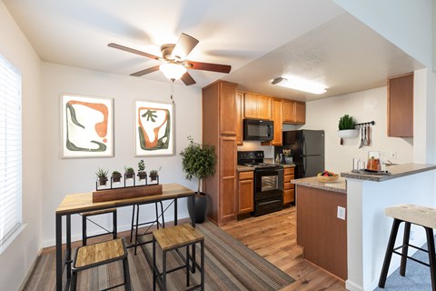 A kitchen with a table and chairs in front of a window at The Woods Apartments, California