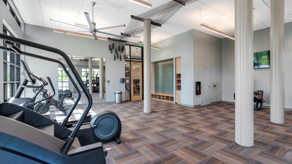 a gym with cardio equipment in a room with pillars