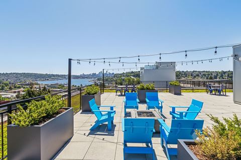 an outdoor patio with blue chairs and a firepit with a view of the water