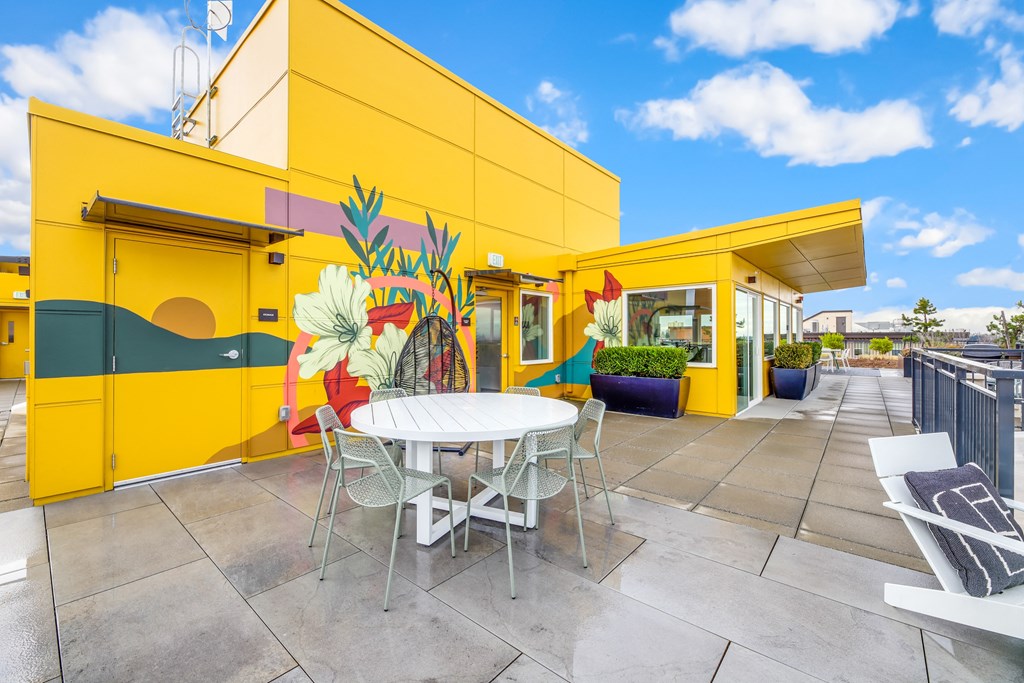 a patio with a table and chairs outside of a yellow building