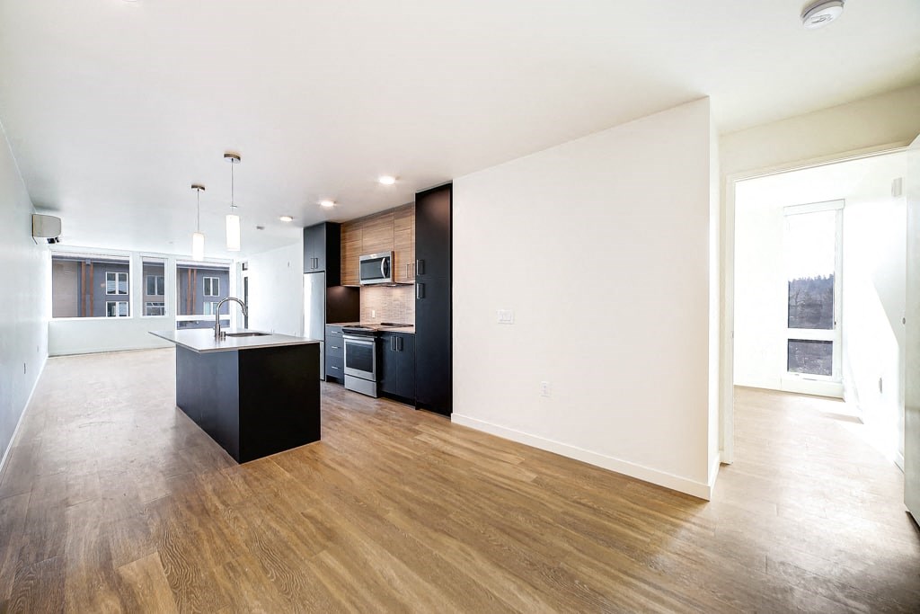 an empty living room with a kitchen with a black