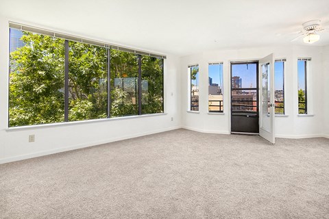 an empty living room with large windows and a door to a balcony