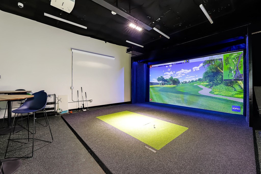 a room with a screen and a golf ball on the ground