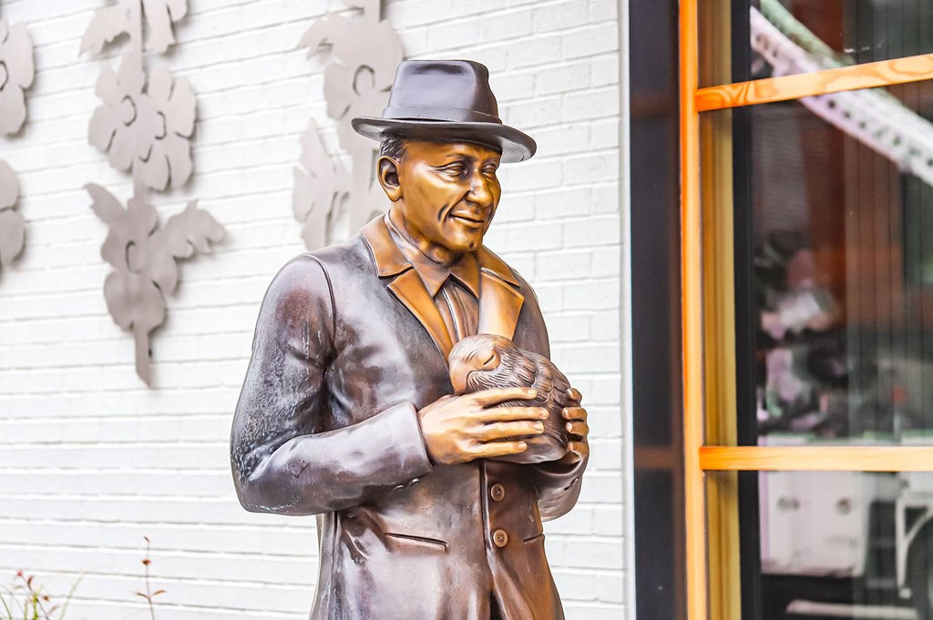 a statue of a man holding a cat in front of a building