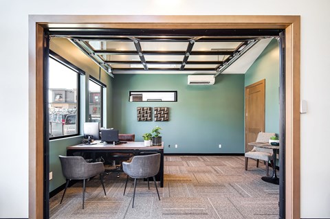 a conference room with a desk and chairs and a green wall
