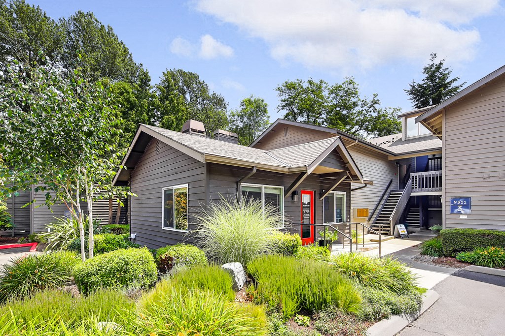 the front of a gray house with a sidewalk and landscaping