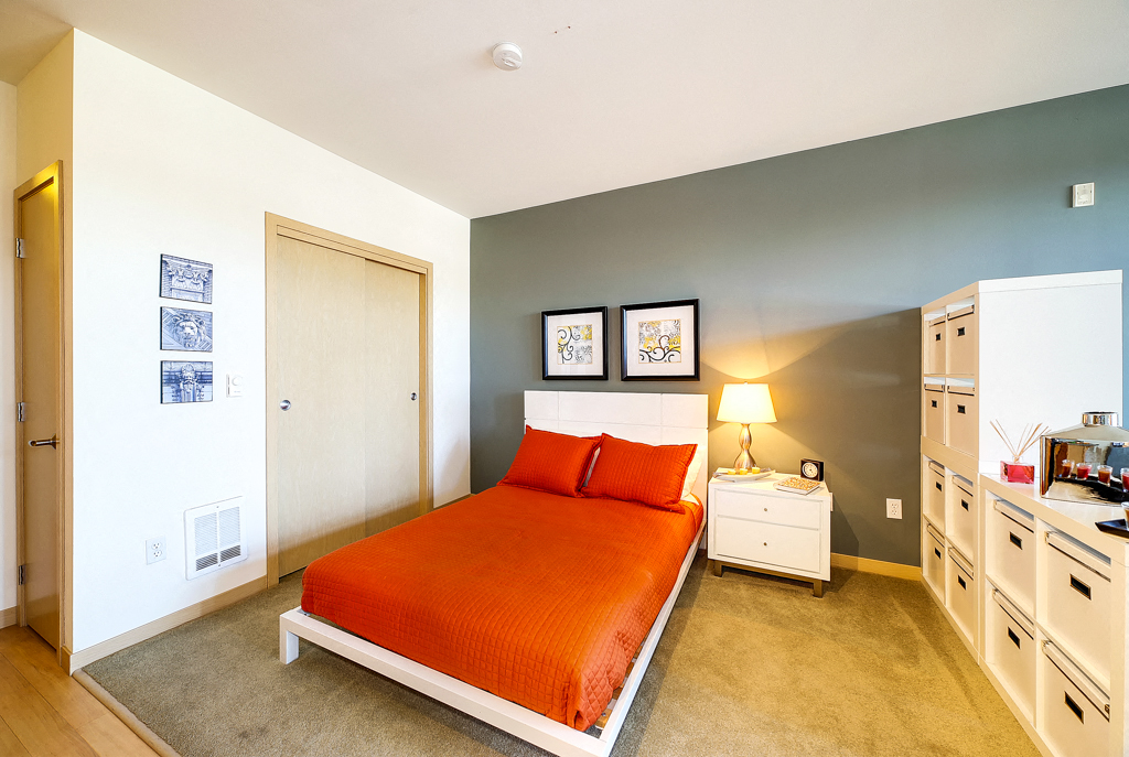 a bedroom with an orange bed and white cabinets