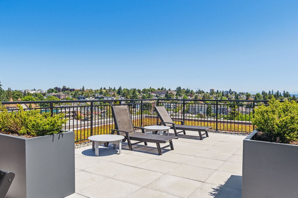 a patio with chairs and tables on a balcony overlooking the city