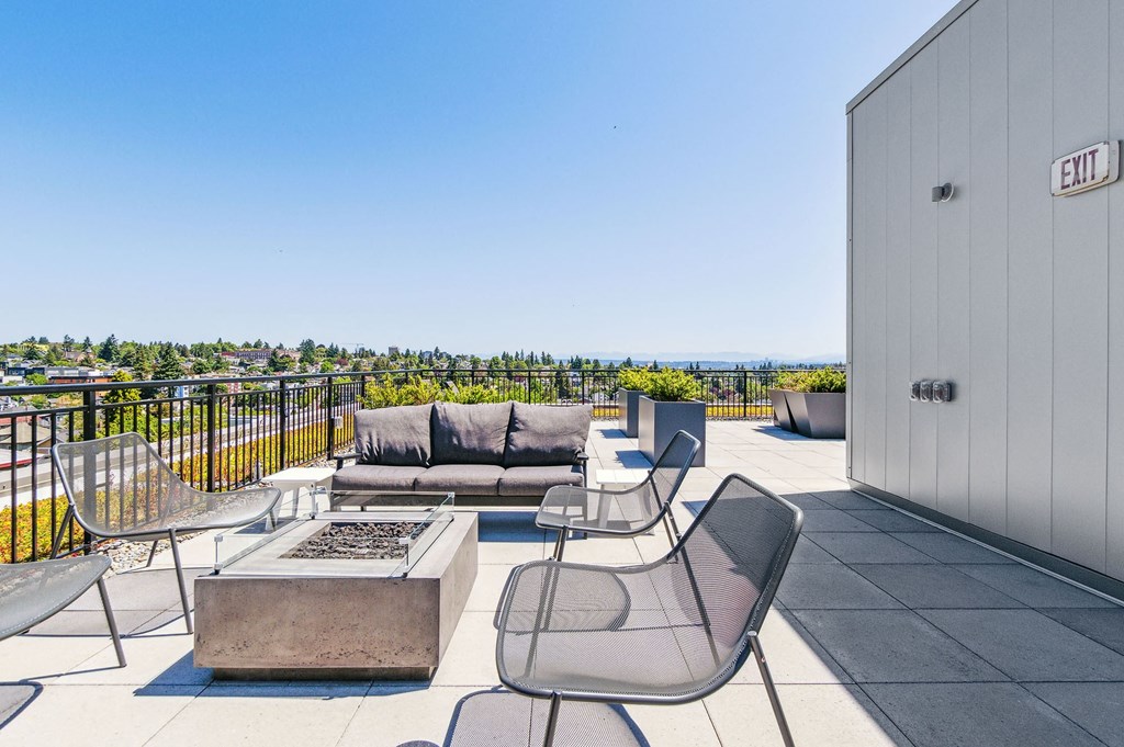 a patio with a firepit and chairs on a roof