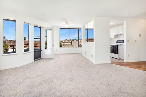 an empty living room with a view of a kitchen and a balcony