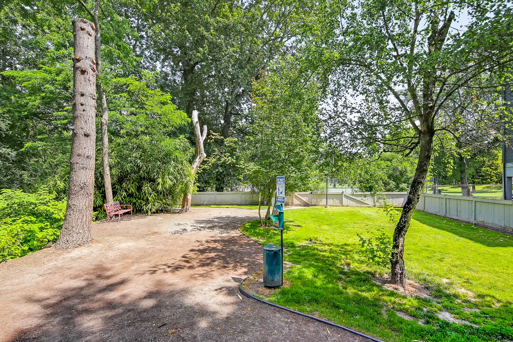 a park with trees and a sign on a dirt path